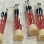 Here's a short alt tag for the image: `Four syringes filled with pink liquid.`